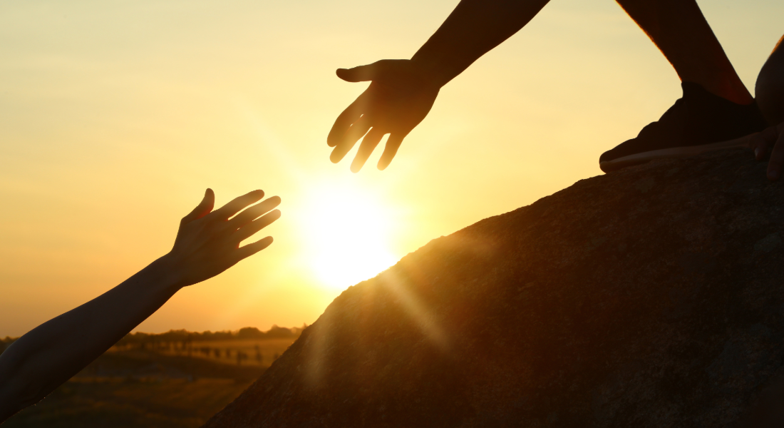 Two hands reaching out towards each other backlit by sunshine